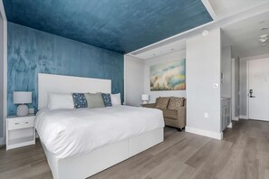 Un dormitorio moderno con una cama grande, una mesita de noche, un sofá y un cuadro en la pared.