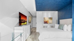 Een moderne slaapkamer met een bed, een televisie en kunstwerken aan de muur.