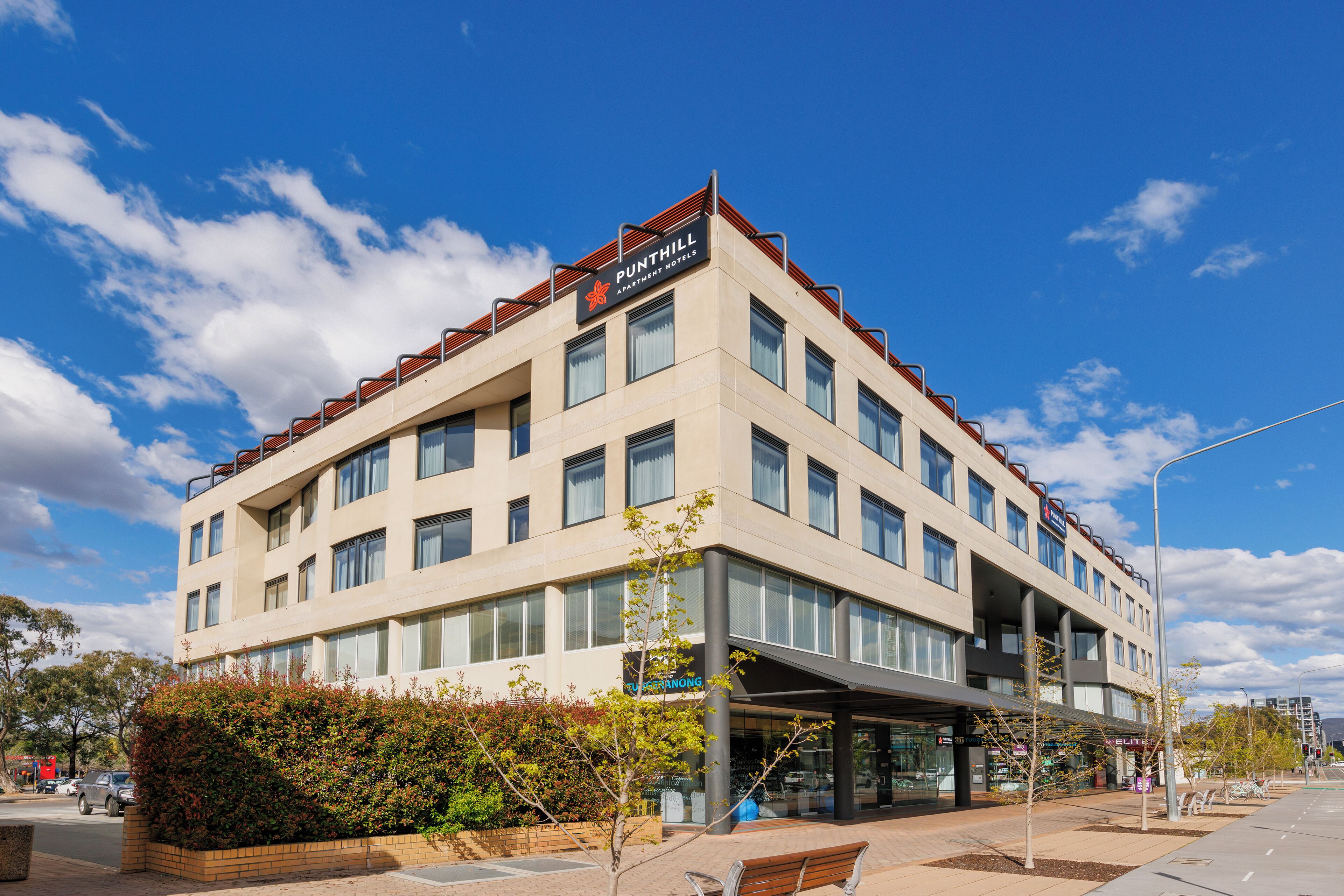 A modern building with a sign for 'PUNTHILL APARTMENT HOTEL'.