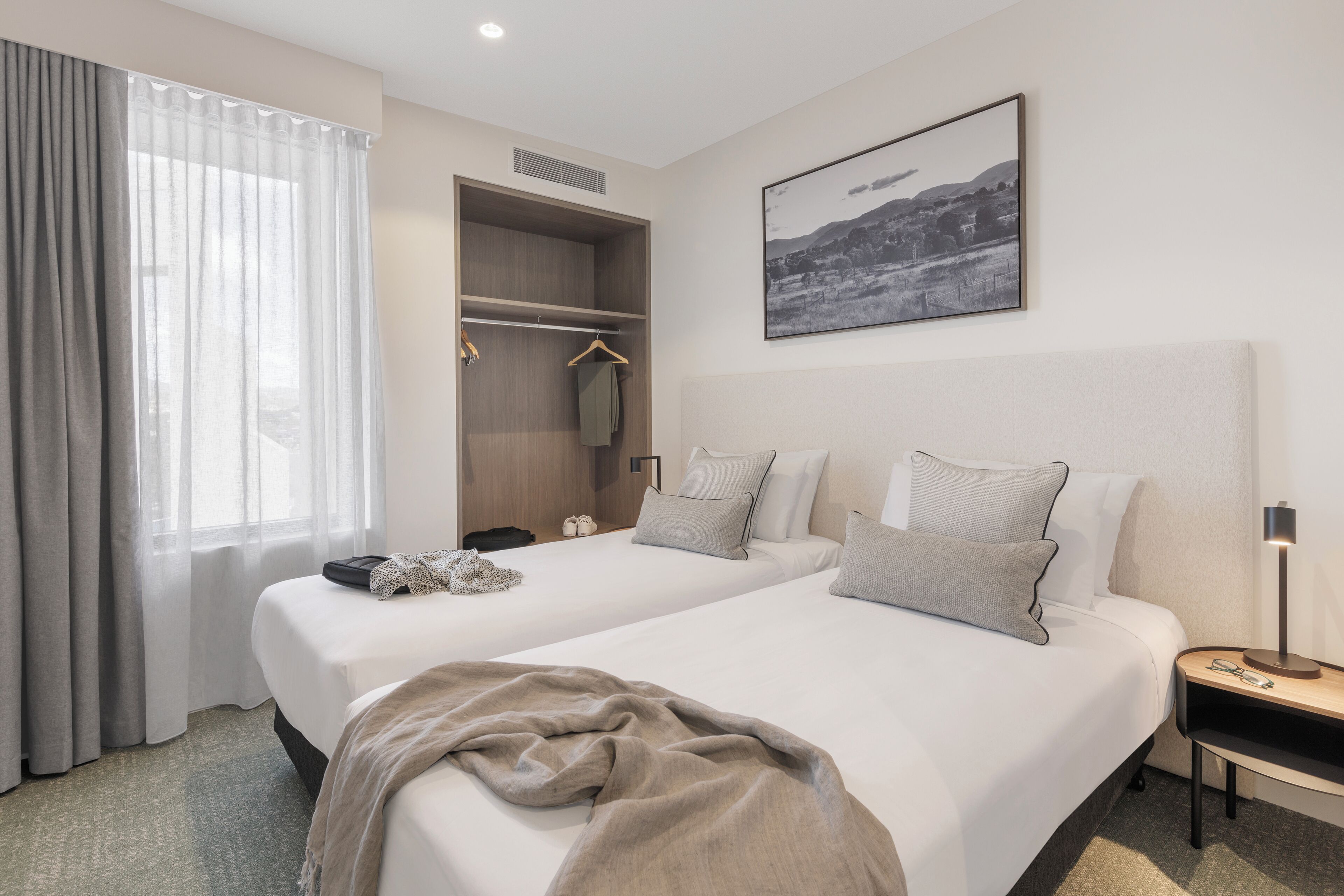 Ein Hotelzimmer mit zwei Betten, einem Schrank, einem Nachttisch und einem Bild an der Wand.