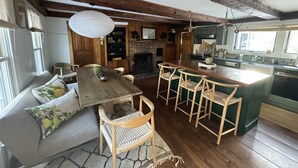 Une cuisine rustique avec des poutres en bois, une cheminée et un coin repas comprenant une table en bois et des tabourets de bar.