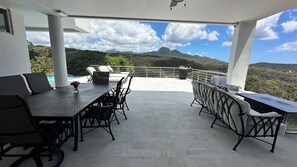 An outdoor patio with a dining table and chairs, a pool, and a scenic mountain view. - Belle La Maye - Azure Room (Castries)