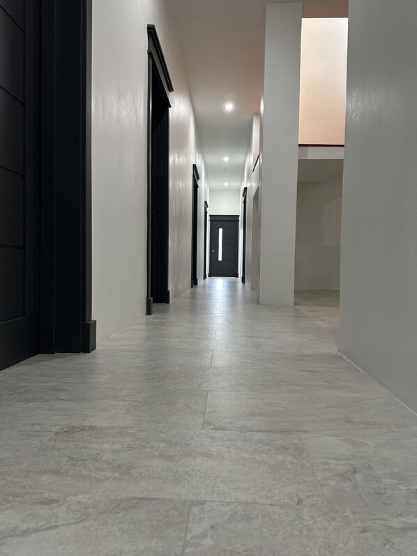 A long, narrow hallway with a tiled floor and white walls.
