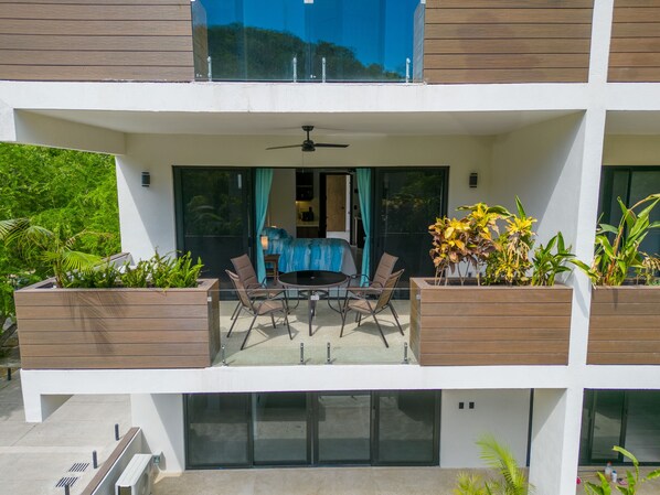 Un apartamento moderno con balcón, un comedor con mesa y sillas, y plantas en macetas.
