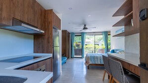 A modern kitchen with wooden cabinets, a built-in oven, and a large window with curtains.