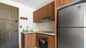 A modern kitchen with wooden cabinets, a stainless steel refrigerator, an oven, and a sink.