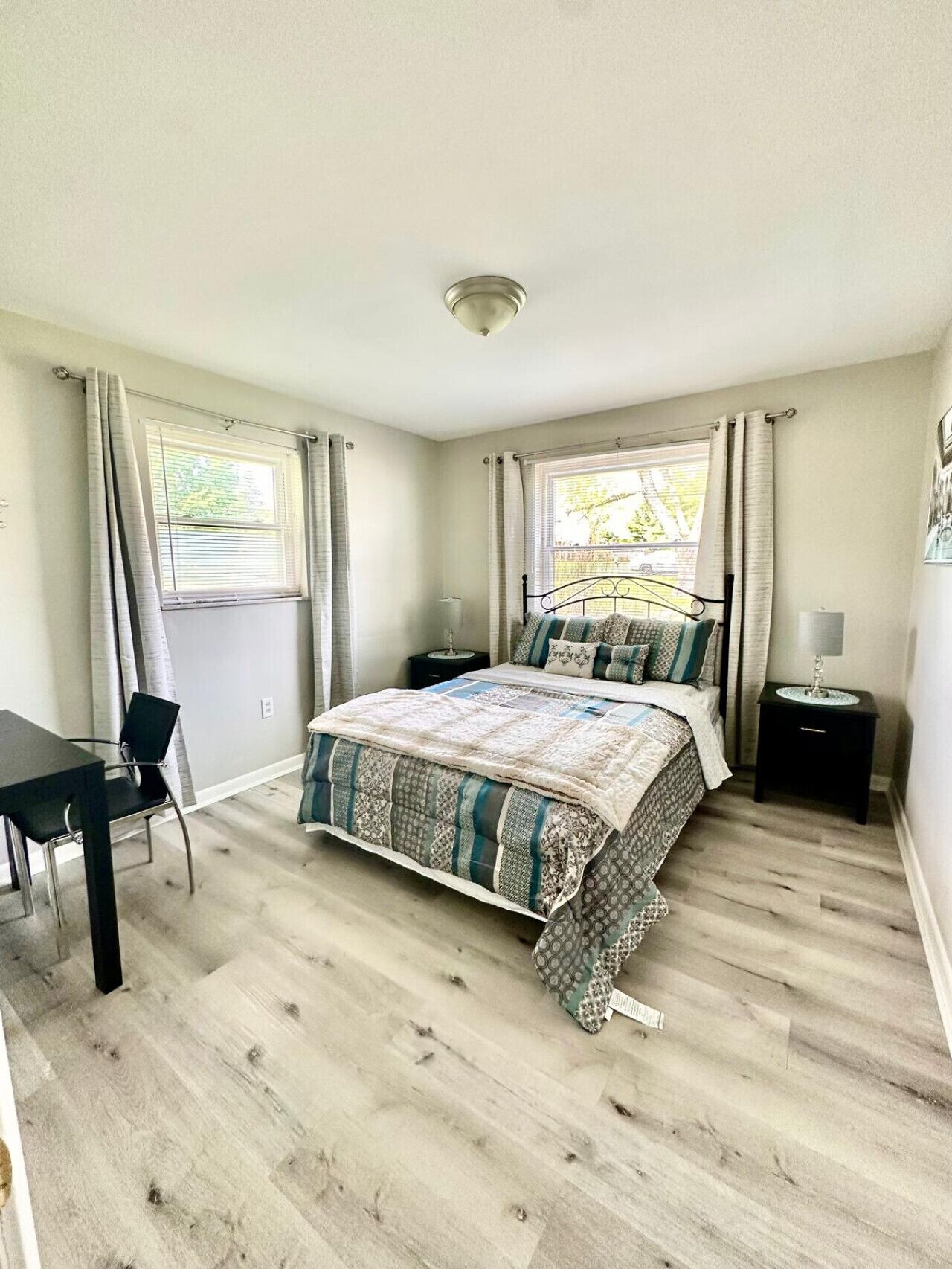 A bedroom with a bed, a desk, and two nightstands.