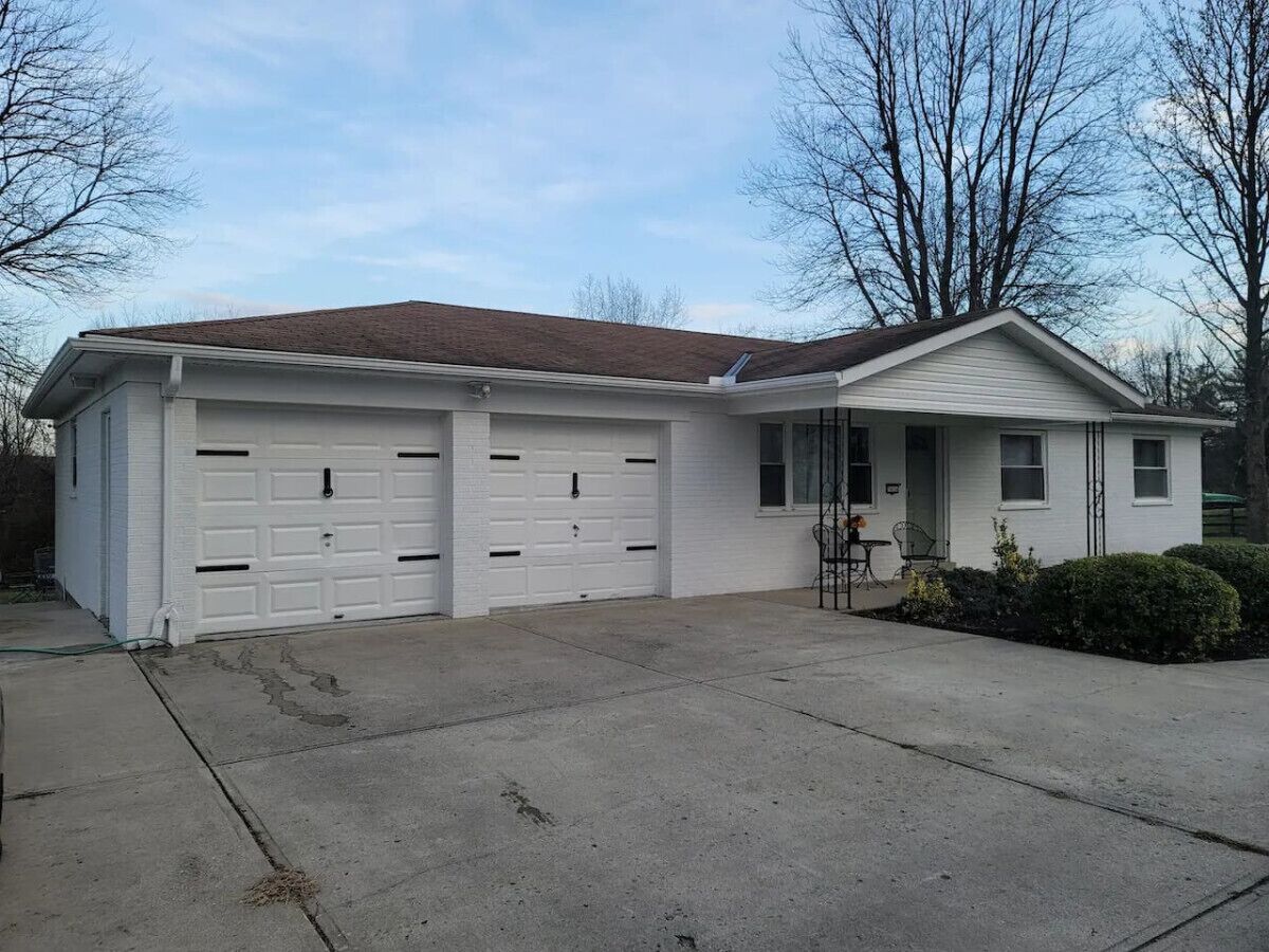 A single-story house with a garage, a front porch, and a small garden.