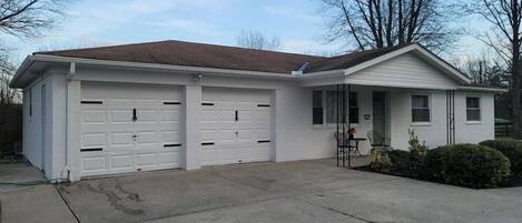 A single-story house with a garage, a front porch, and a small garden.