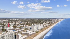 A coastal cityscape with a beachfront, high-rise residential buildings, and a clear sky. - Pool,1 Block to Beach, Sleeps 10, Golf Cart, Main ST (North Myrtle Beach)