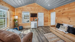 A cozy cabin interior with a wooden interior, a sofa, a coffee table, and a kitchen area.