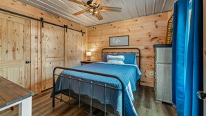 A bedroom with a bed, a nightstand, a ceiling fan, and a wardrobe.