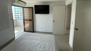 A bedroom with a bed, a TV mounted on the wall, and a door leading to a balcony. - Apartamento AL2-P Cerca al Mar con Pisci (Cartagena)