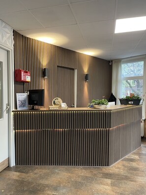 A reception desk with a modern design, a fire extinguisher, a monitor, and a sign for Flex-Inn WiFi. - Flex-Inn (Rotterdam)