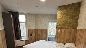 Un dormitorio con cama, radiador, ventana y puerta.