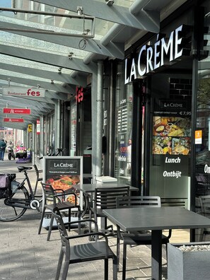 An outdoor seating area with tables and chairs in front of a restaurant named "LA CREME". - Flex-Inn (Rotterdam)
