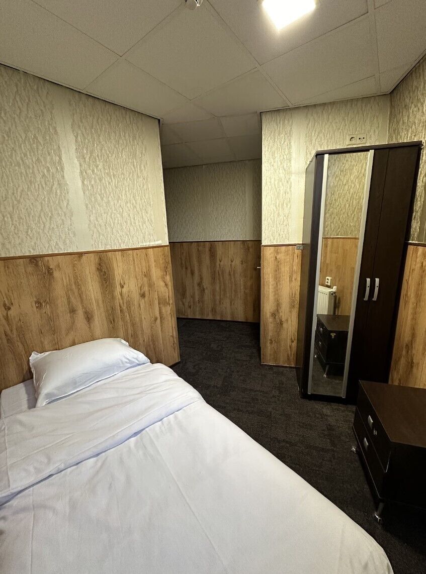 A hotel room with a bed, a wardrobe, and a mirror.