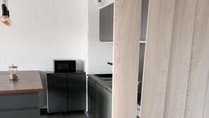 Una cocina moderna con armarios grises, encimera de madera y microondas integrado.