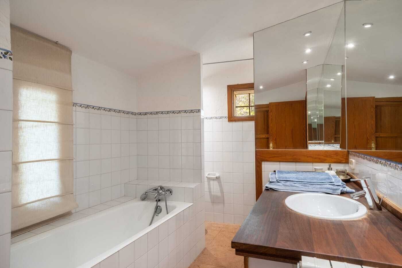 A bathroom with a bathtub, a sink, and a large mirror.