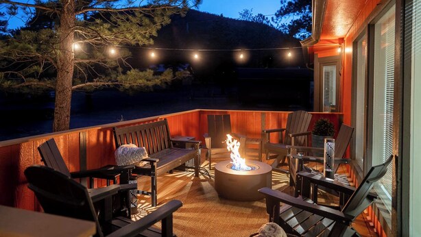An outdoor deck with a fire pit, seating, and string lights.