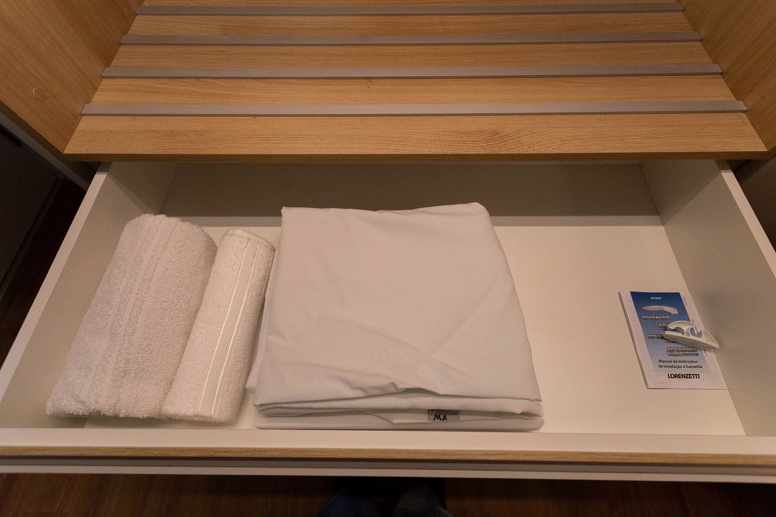 A neatly organized drawer with folded towels and a maintenance manual.