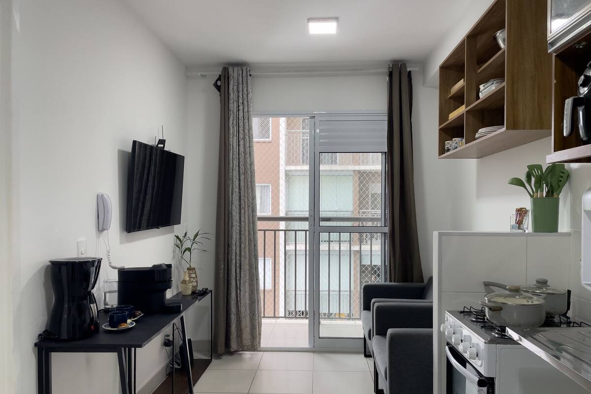 A compact kitchen with a gas stove, a coffee maker, and a small dining area with a table and chairs.