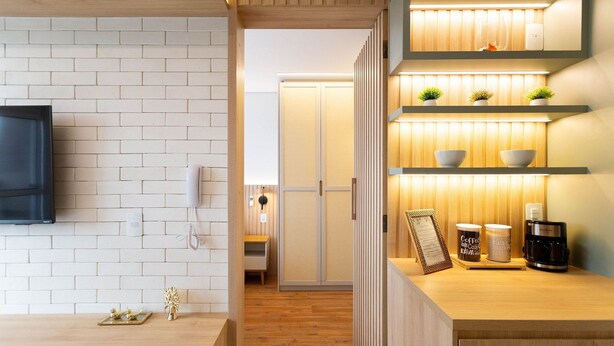 A modern kitchen with a wooden countertop, white brick backsplash, and built-in shelves with plants and kitchenware. - Studio Laguna (São Paulo)