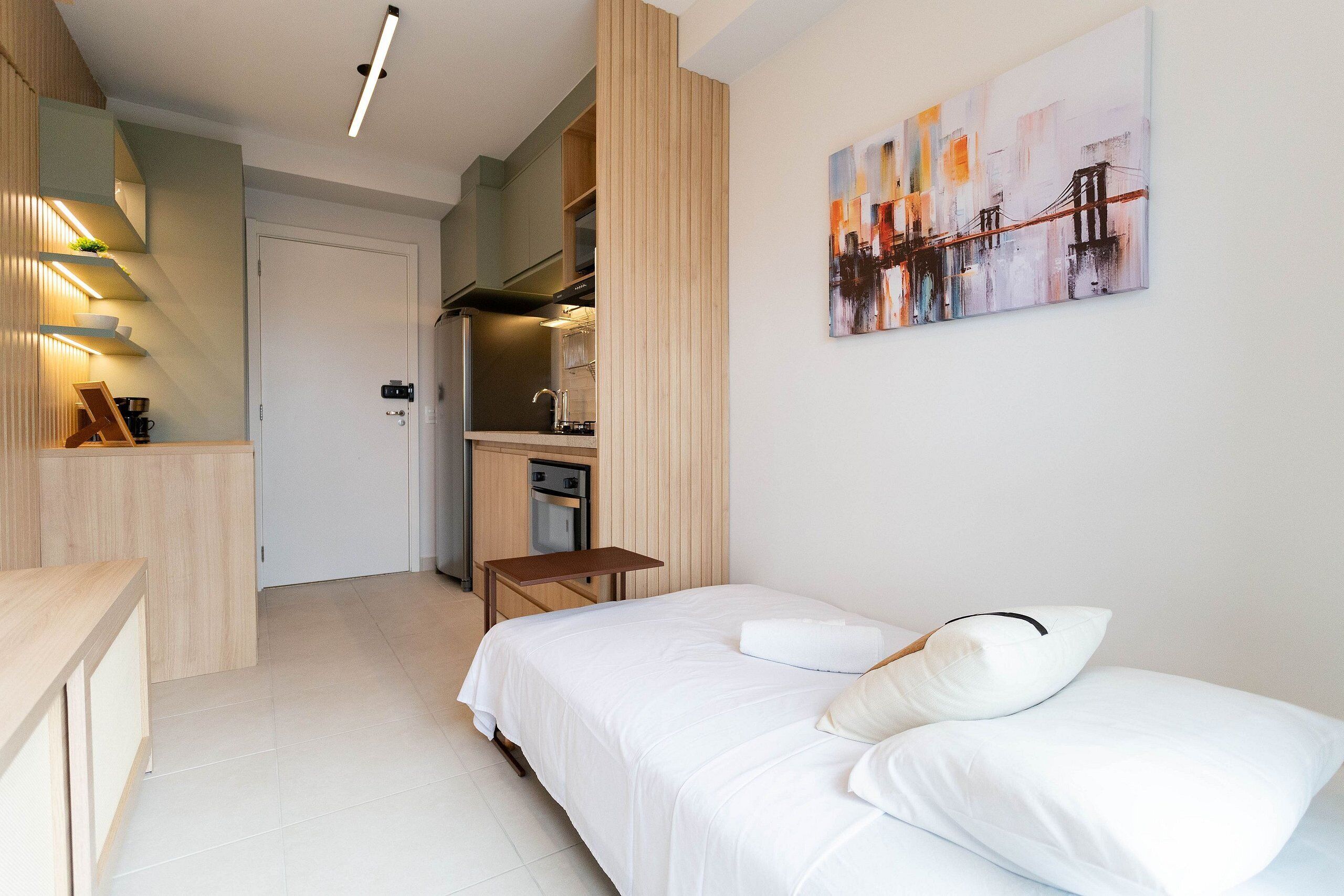 Una moderna camera d'hotel con un letto, una scrivania, angolo cottura e un quadro appeso al muro.