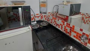 A compact kitchen with a microwave, stove, and sink. - SuhcasaCopacabana 50 Ocean View (Rio de Janeiro)