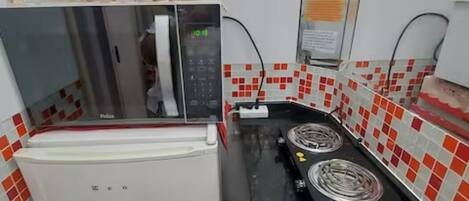 Una cocina compacta equipada con refrigerador, microondas y estufa.