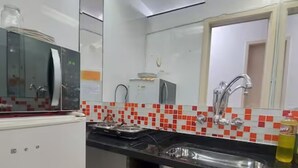 A compact kitchen with a microwave, sink, and tiled backsplash. - SuhcasaCopacabana 50 Ocean View (Rio de Janeiro)
