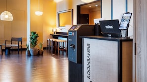 A reception desk with a laptop, a digital screen, and a sign reading "BIENVENIDOS B&BHOTELS".