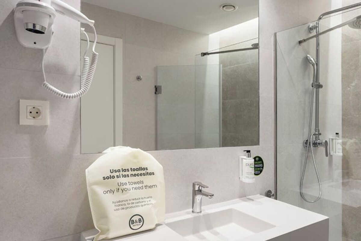 A modern bathroom with a glass-enclosed shower, a white sink, and a mirror.
