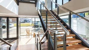 A modern interior with a staircase, glass doors, and a view of the outside.