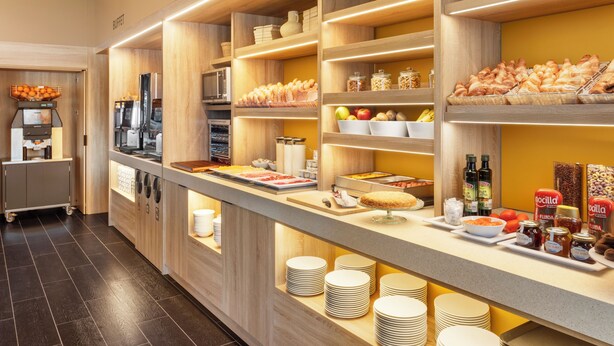 A buffet area with wooden shelves, a coffee station, and various food items.