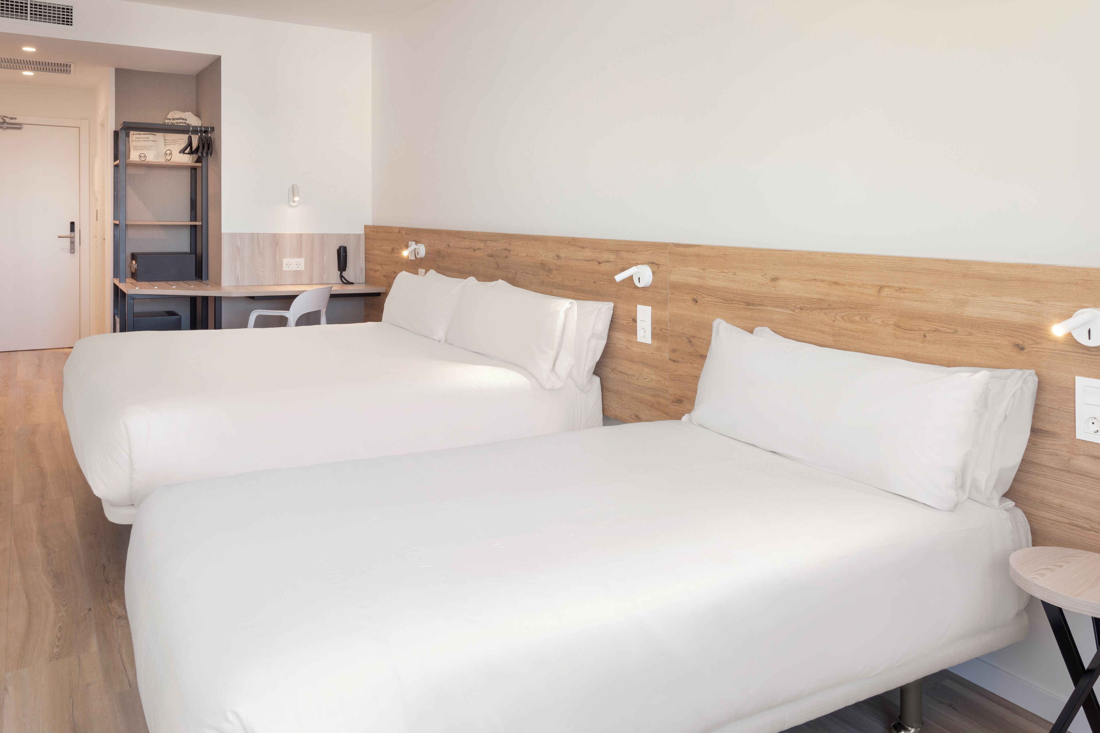 Una habitación de hotel con dos camas, un escritorio y una mesita.
