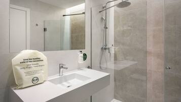 A modern bathroom with a white sink, a glass shower enclosure, and a mirror.