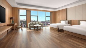 Quarto de hotel moderno com uma cama grande, um sofá, uma escrivaninha e uma televisão.