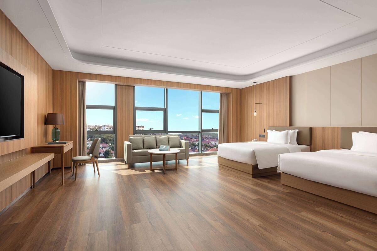 Ein modernes Hotelzimmer mit einem großen Bett, einer Couch, einem Schreibtisch und einem Fernseher.