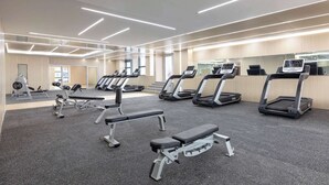 Uma academia com esteiras, bancos e máquinas de musculação.