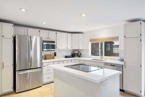 A modern kitchen with white cabinetry, stainless steel appliances, and a central island.