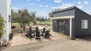 Un espace patio aménagé avec du mobilier d’extérieur, un petit abri de jardin et un bâtiment doté d’une pergola.