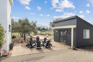Un espace patio aménagé avec du mobilier d’extérieur, un petit abri de jardin et un bâtiment doté d’une pergola.