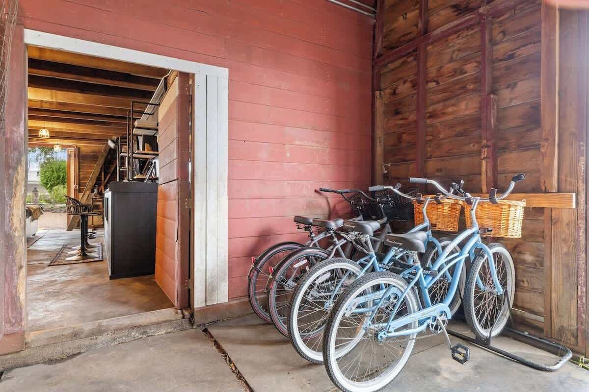 A wooden barn with a red exterior, a staircase leading to an upper level, and bicycles parked inside.