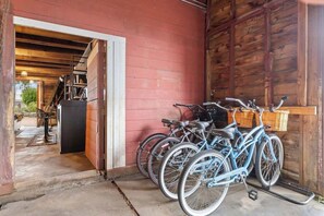 A wooden barn with a red exterior, a staircase leading to an upper level, and bicycles parked inside.