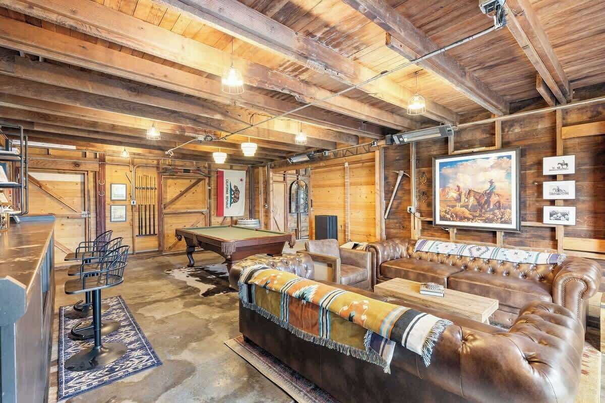 A rustic interior with a pool table, leather seating, and wooden walls.