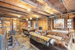 Un intérieur rustique avec un billard, des fauteuils en cuir et des murs en bois.