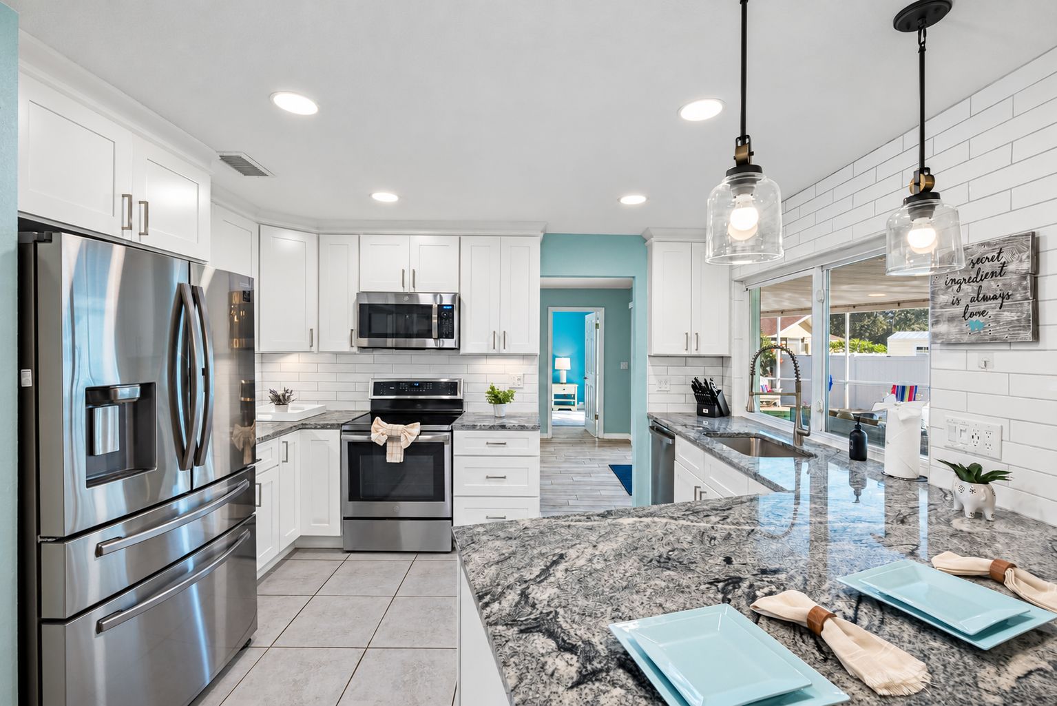 A modern kitchen with stainless steel appliances, white cabinetry, and a granite countertop.