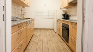 A compact kitchen with wooden cabinets, a white refrigerator, a coffee maker, and a dishwasher. - Close to City Center - Affordable Private Rooms with TV (Vienna)
