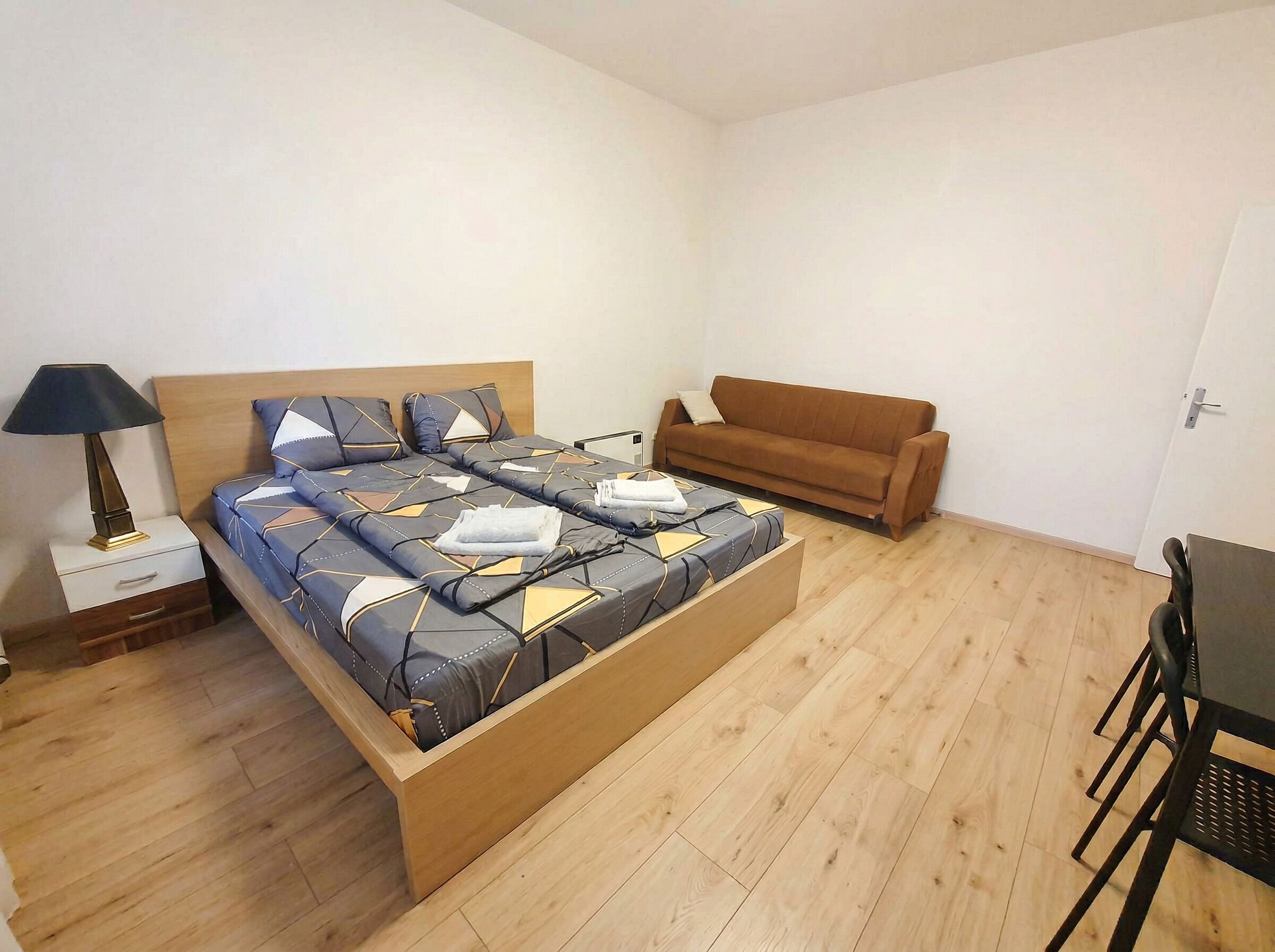Une chambre à coucher avec un lit, une table de chevet, une lampe, un canapé et une table.